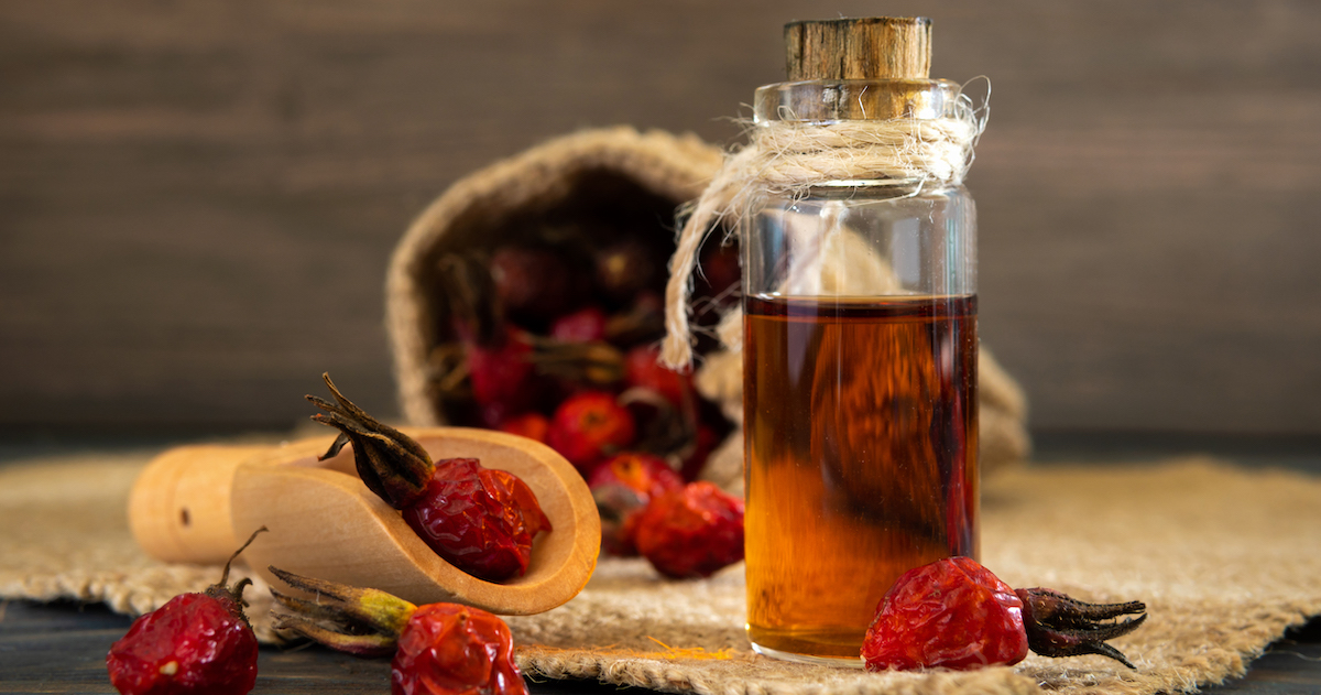 rosehip-oil-wooden-boards-dark-background-bottle-is-tied-with-cord-with-dogrose-essential-oil-bag-berries